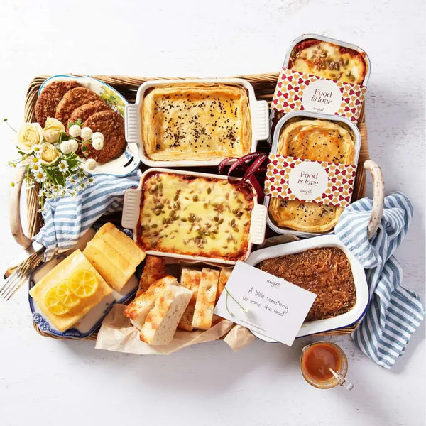 Food hamper with lasagna, pies, lemon cake, bread, cookies, and a gift card arranged in a basket.
