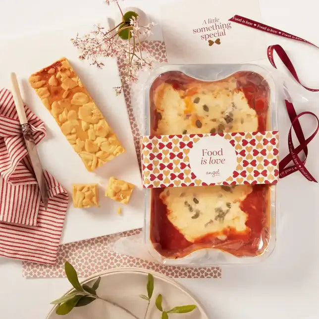 Packaged lasagna with Angel Delivery sleeve and almond loaf cake on a table.