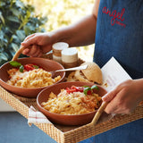 Tray with two bowls of creamy pasta topped with tomatoes and basil, served with bread rolls and a gift card from Angel Delivery.
