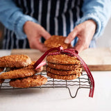 Stack of oat cookies tied with ribbon, person arranging cookies in background