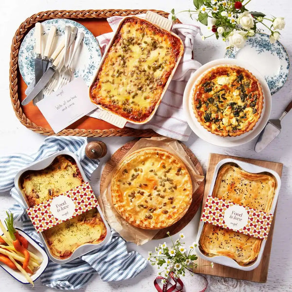 Assortment of pies and quiches in trays with Angel Delivery branding on a white table